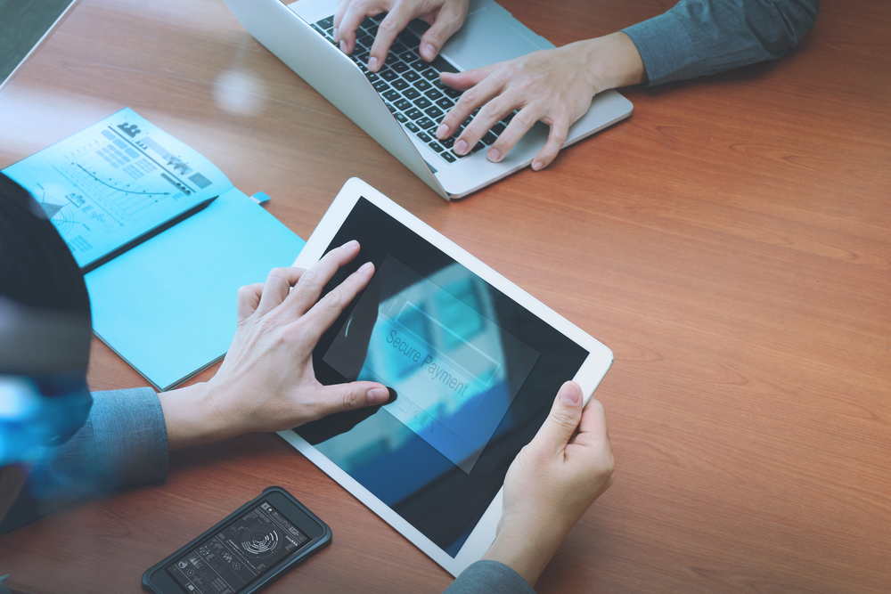 top view of two colleagues using digital pro tablet and laptop computer with "Secure payment" on the screen as Online shopping concept